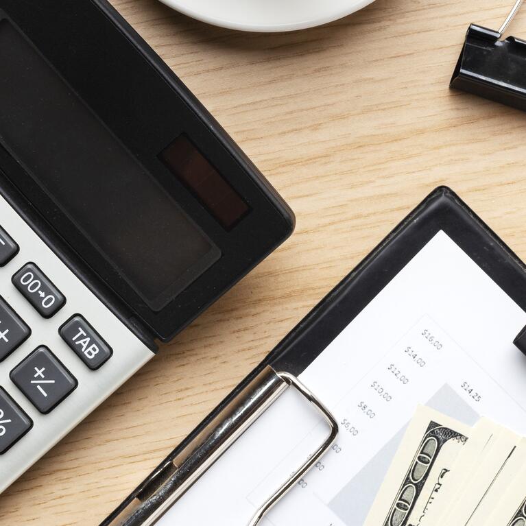 A calculator and a calendar next to some cash 